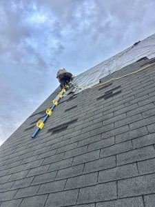Birds Eye Roofing crew member tearing off old shingles during a roof replacement